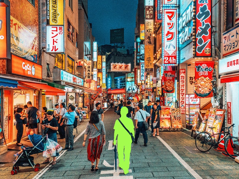 Ilustración fotográfica de personas paseando por el distrito de Shinjuku, en Tokio, Japón. Una de las personas lleva una capa verde que indica que es IA.