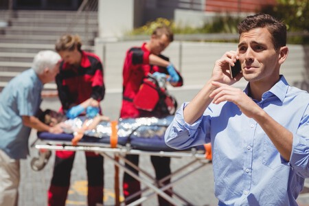 Hombre Hablando Por Telefono Movil Y Paramedicos Examinando Nino Herido En Segundo Plano