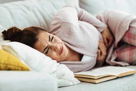 Mujer Joven Que Siente Dolor En El Abdomen Mientras Se Acuesta En El Sofa En Casa