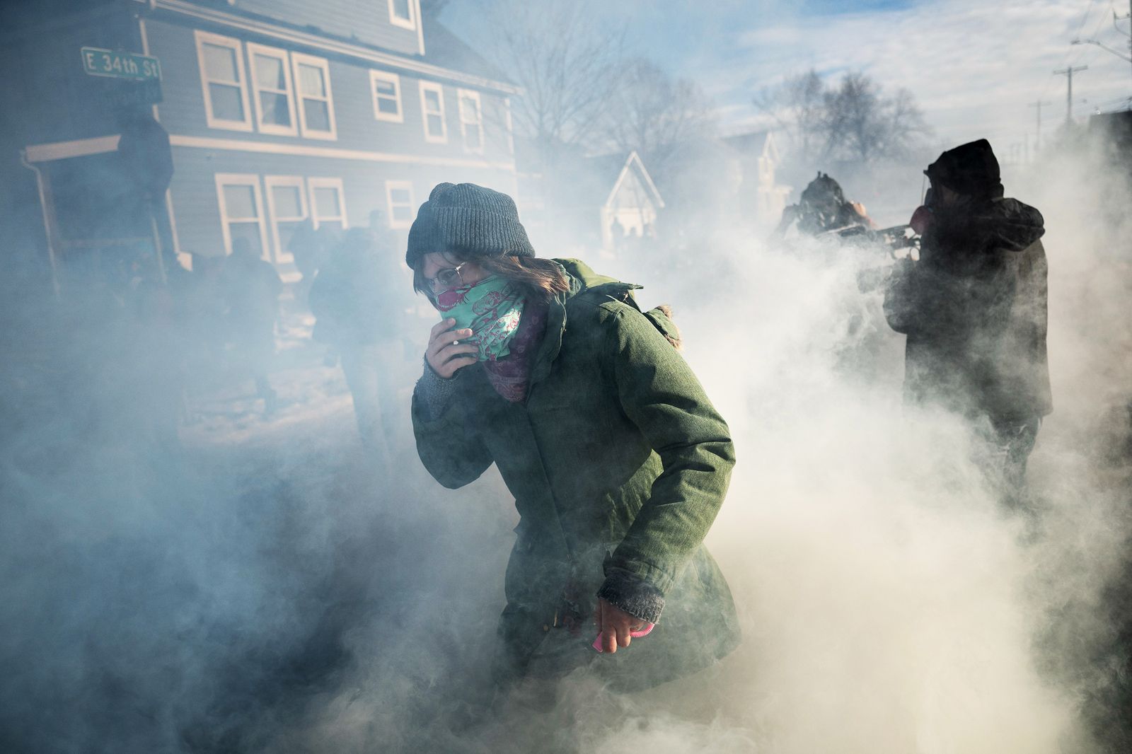 Observadores y manifestantes caminan entre gases lacrimógenos tras enfrentarse a agentes federales durante una redada en...